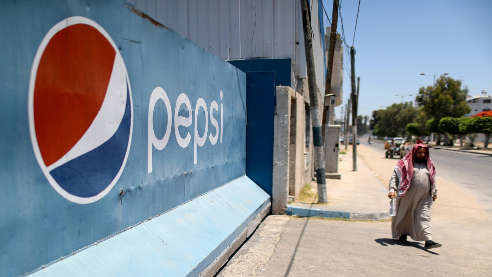 فلسطيني يمر بجانب مصنع بيبسي غزة للمشروبات الغازية في مدينة غزة، 21 يونيو 2021. (رويترز)