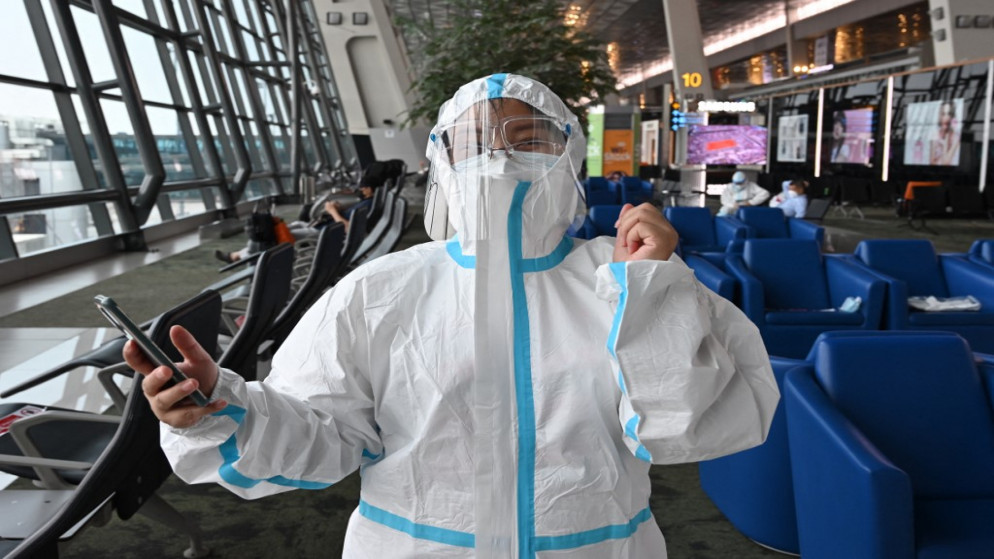 شخص على حدود شنتشن في الصين يضع معدات الحماية الشخصية للوقاية من كورونا قبل الوقوف في طابور لركوب طائرة، 8 حزيران/ يونيو 2021 (رويترز)