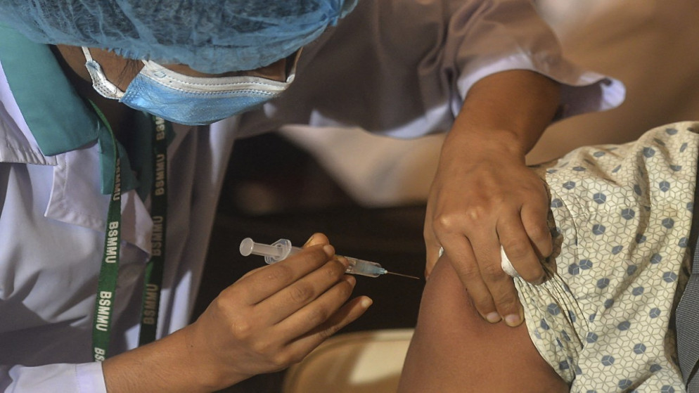عامل صحي يعطي رجلا جرعة من لقاح أسترازينيكا في مستشفى في دكا، 22 حزيران/يونيو 2021. (أ ف ب)