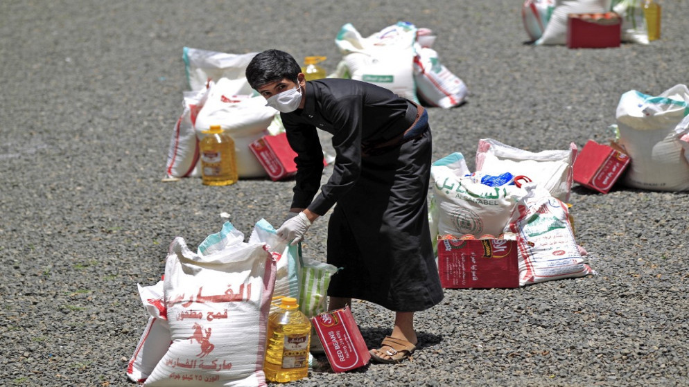 شاب يمني يحمل جزءًا من مساعدات غذائية، في العاصمة اليمنية صنعاء، 17 أيار/مايو 2020. (أ ف ب)