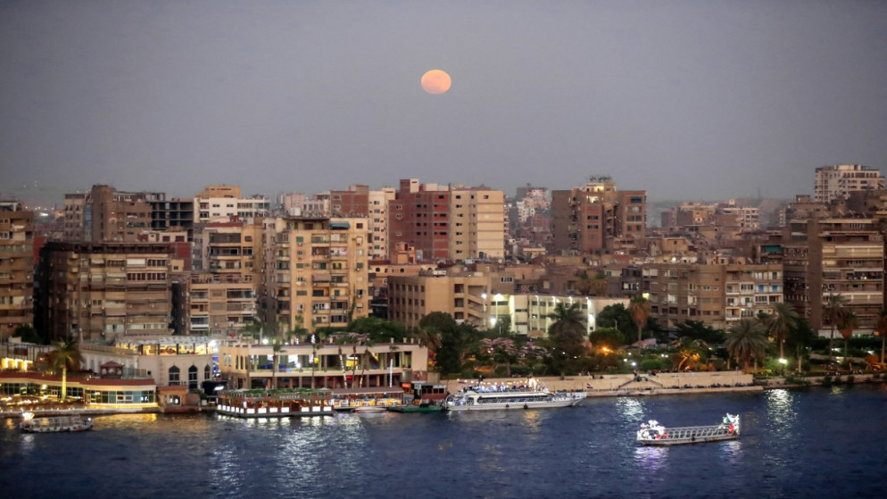 صورة تظهر القمر يرتفع فوق المباني في العاصمة المصرية القاهرة. 24 حزيران/ يونيو 2021. (أ ف ب)
