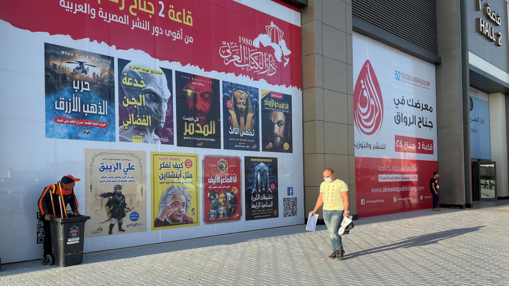 رجل يرتدي كمامة ويحمل كتبا خلال معرض القاهرة الدولي للكتاب 52 في مركز مصر الدولي للمعارض في القاهرة، مصر، 4 تموز/يوليو 2021. (رويترز / سامح الخطيب)