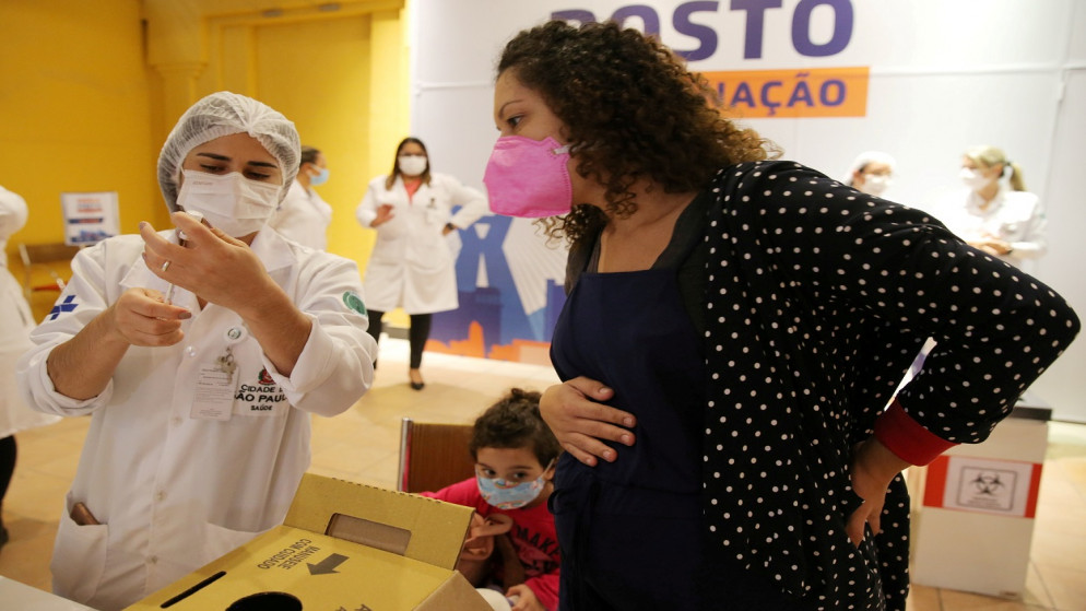 امرأة برازيلية حامل، تراقب ممرضة قبل تلقي جرعة من لقاح فيروس كورونا، من فايزر في ساو باولو، البرازيل، 7 حزيران/ يونيو 2021. (رويترز)