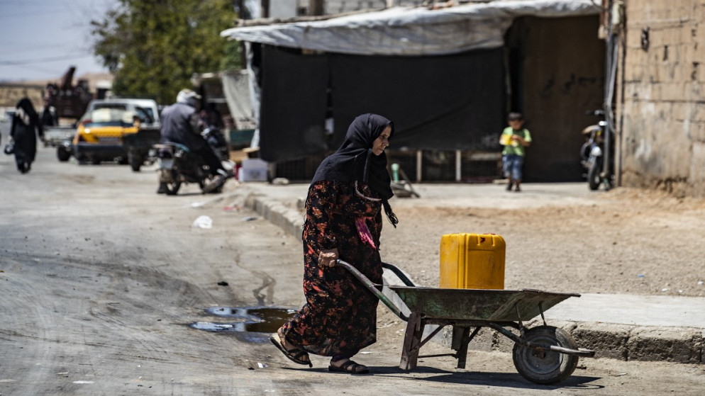 امرأة سورية تحمل عبوة مياه في شمال شرق سوريا. (أ ف ب)