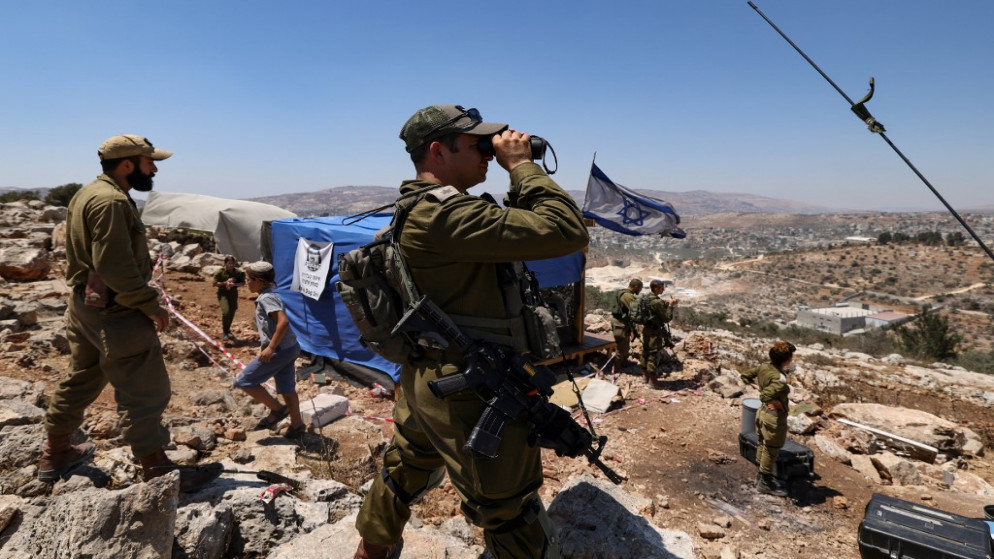 جنود إسرائيليون يراقبون قرية بيتا الفلسطينية بمنظار بينما يقوم المستوطنون بإخلاء البؤرة الاستيطانية التي تم إنشاؤها حديثًا في إيفياتار في بيتا ، بالقرب من مدينة نابلس شمال فلسطين في الضفة الغربية المحتلة ، في 2 يوليو ، 2021.