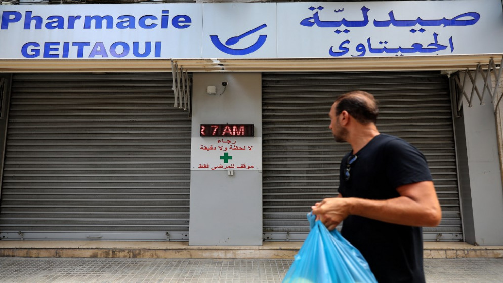 رجل يحدق في باب مغلق لإحدى الصيدليات في العاصمة اللبنانية بيروت، خلال إضراب على مستوى البلاد للصيدليات احتجاجا على النقص الحاد في الأدوية ، 9 تموز/يوليو 2021 (أ ف ب)