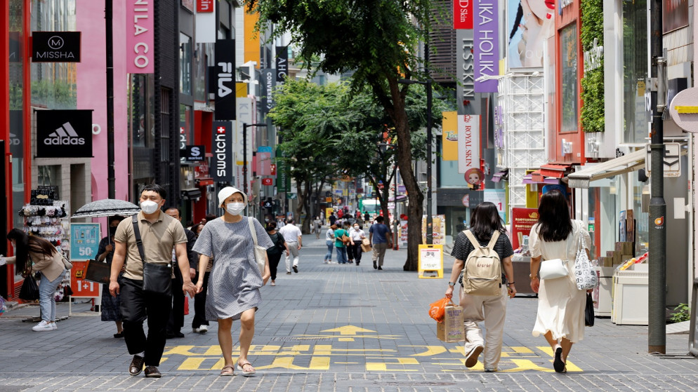 أشخاص يرتدون كمامات للوقاية من كورونا يسيرون في منطقة تسوق في سول بكوريا الجنوبية، 9 تموز/يوليو 2021. (رويترز)