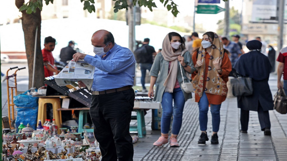 إيرانيون يرتدون أقنعة الوجه كإجراء ضد فيروس كورونا كوفيد -19، في أحد شوارع العاصمة طهران، في 7 يوليو / تموز 2021. (أتا كيناري /أ ف ب)