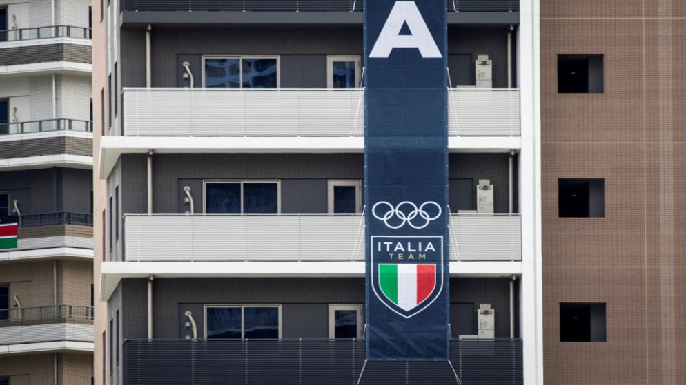 علم وراية الفريق الإيطالي على مبنى في القرية الأولمبية بطوكيو. 14 يوليو 2021.(أ ف ب)
