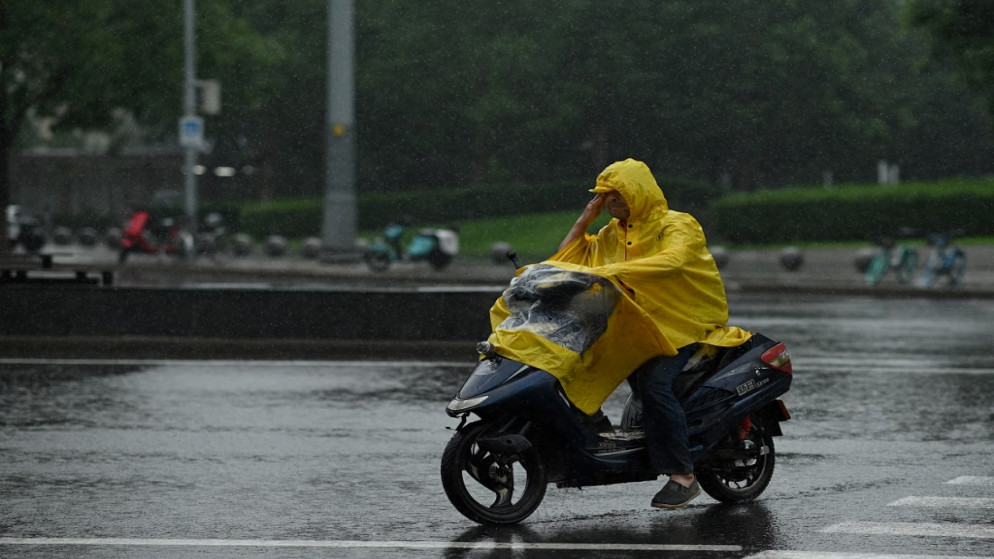 سائق دراجة نارية يرتدي سترة مطر مع هطول الأمطار في بكين في 12 تموز/يوليو 2021. (أ ف ب)