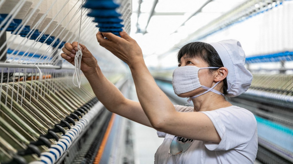 موظفة تعمل في مصنع نسيج في نانتونغ بمقاطعة غيانغ سو شرقي الصين. 15/07/2021. (أ ف ب)
