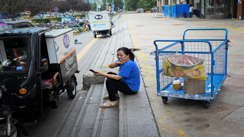 عاملة توصيل تستريح خارج مركز تسوق في بكين في 15 تموز/يوليو 2021.(أ ف ب)