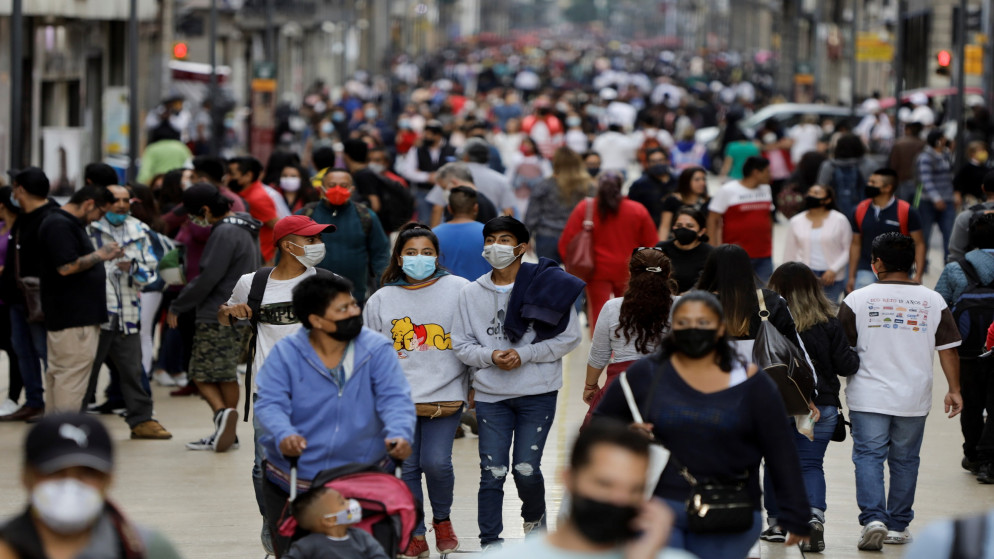 أناس يسيرون في شارع عام وسط التزام بارتداء الكمامات في المكسيك. (رويترز)