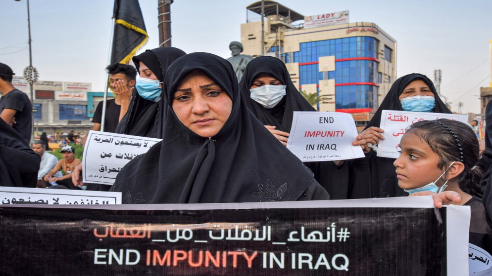 نساء يرفعن لافتات احتجاجية تطالب السلطات العراقية بمحاسبة قتلة عشرات النشطاء، خلال تظاهرة في ساحة الحبوبي في مدينة الناصرية جنوبي العراق، 18 يوليو / تموز 2021. (أ ف ب)