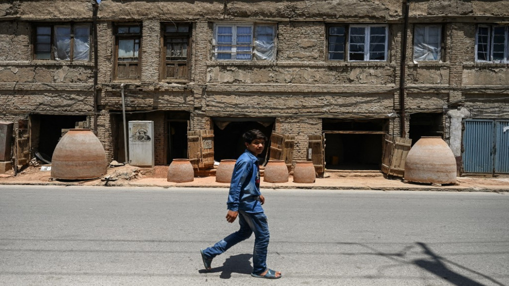 صبي يمشي أمام متجر يبيع أفرانًا طينية على طول الطريق في كابُل .18 تموز/يوليو 2021.(أ ف ب)