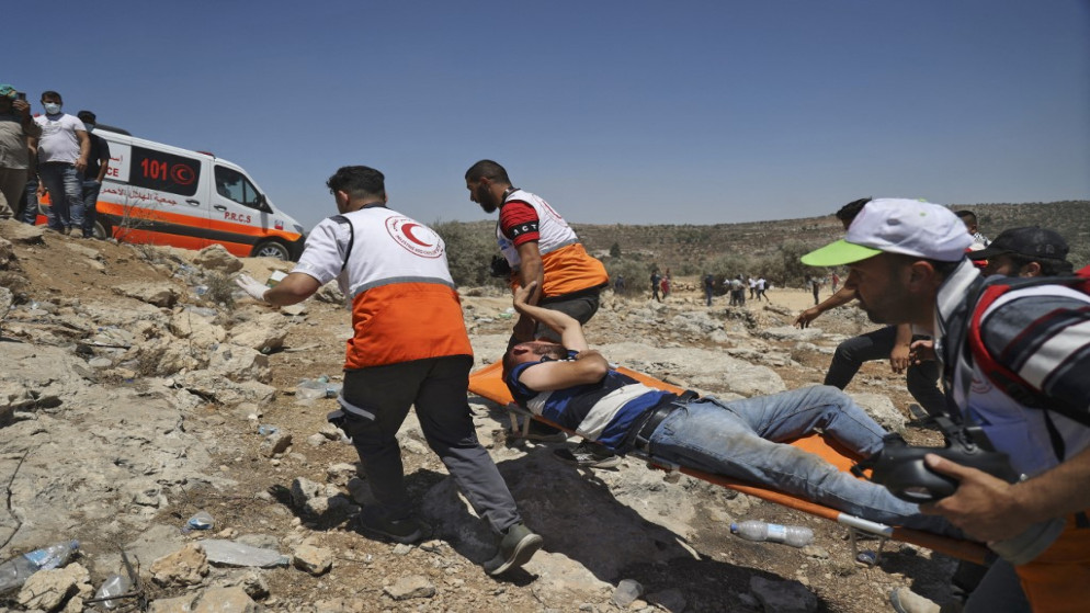 الهلال الأحمر الفلسطيني يخلي متظاهرا مصابا خلال مواجهات مع القوات الإسرائيلية في بلدة بيتا ، بالقرب من مدينة نابلس بالضفة الغربية المحتلة.9 يوليو ، 2021.(أ ف ب)