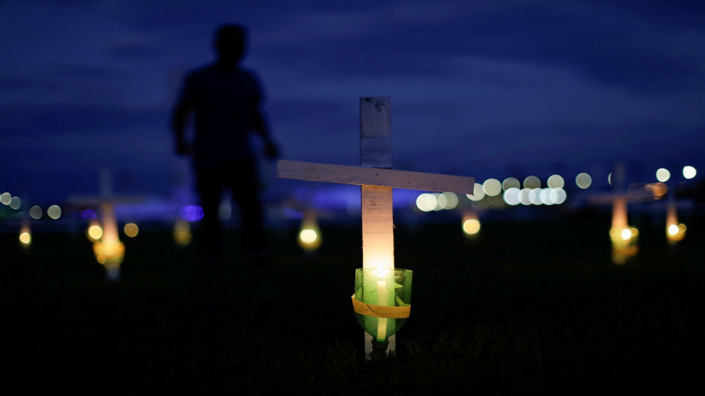 شمعة وصليب يرمزان إلى الأشخاص الذين ماتوا بسبب الفيروس، أمام المؤتمر الوطني في برازيليا، البرازيل، 27 نيسان/ أبريل 2021. (رويترز)