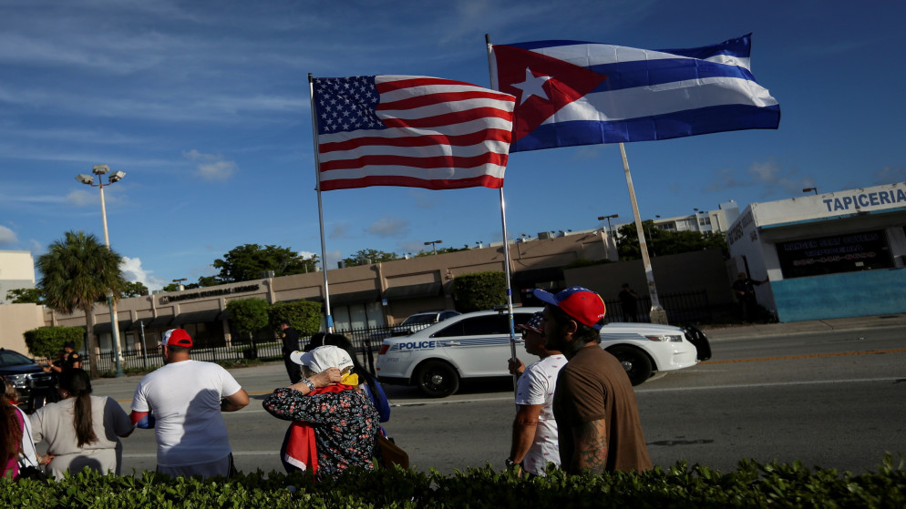 أشخاص يلوح بالأعلام الأميركية والكوبية خارج مطعم في ميامي بالولايات المتحدة في ردهم على تقارير عن احتجاجات في كوبا ضد اقتصادها المتدهور. 18/07/2021. (ماركو بيلو /أ ف ب)