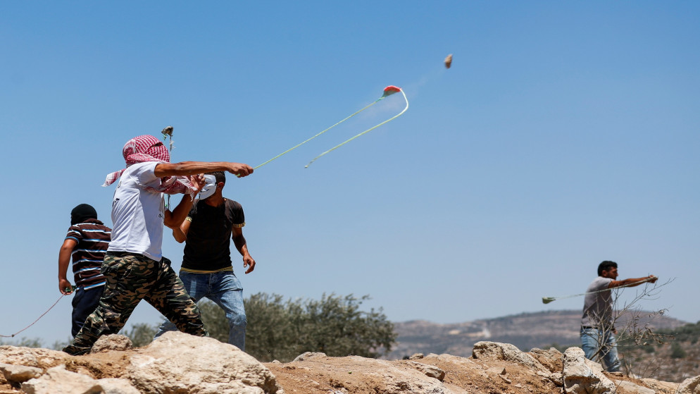 متظاهرون فلسطينيون يستخدمون المقلاع ضد قوات الاحتلال الإسرائيلي خلال مظاهرة في بيتا في الضفة الغربية المحتلة، 9 تموز/يوليو 2021. (رويترز)