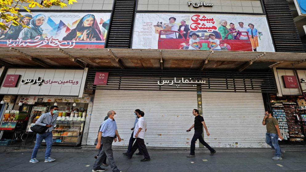 إيرانيون يمشون أمام قاعة سينما مغلقة وسط مدينة طهران في 20 يوليو 2021. (أ ف ب)