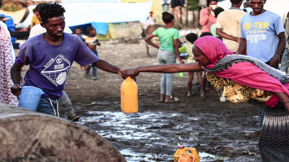 لاجئ إثيوبي فر من القتال العنيف في موطنه تيغراي، يتلقى جرنًا من الماء في مركز الاستقبال الحدودي في مدينة حمدية بولاية كسلا بشرق السودان، في 14 نوفمبر/ تشرين الثاني 2020. (رويترز)