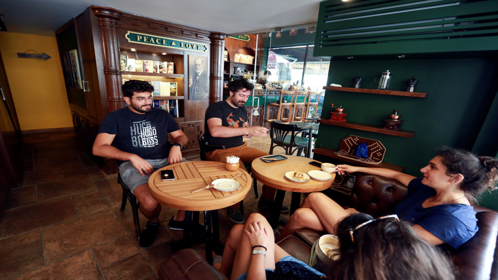أشخاص يجلسون في مقهى تعرض لأضرار في أعقاب انفجار مرفأ بيروت، 23 تموز/يوليو 2021. (رويترز)