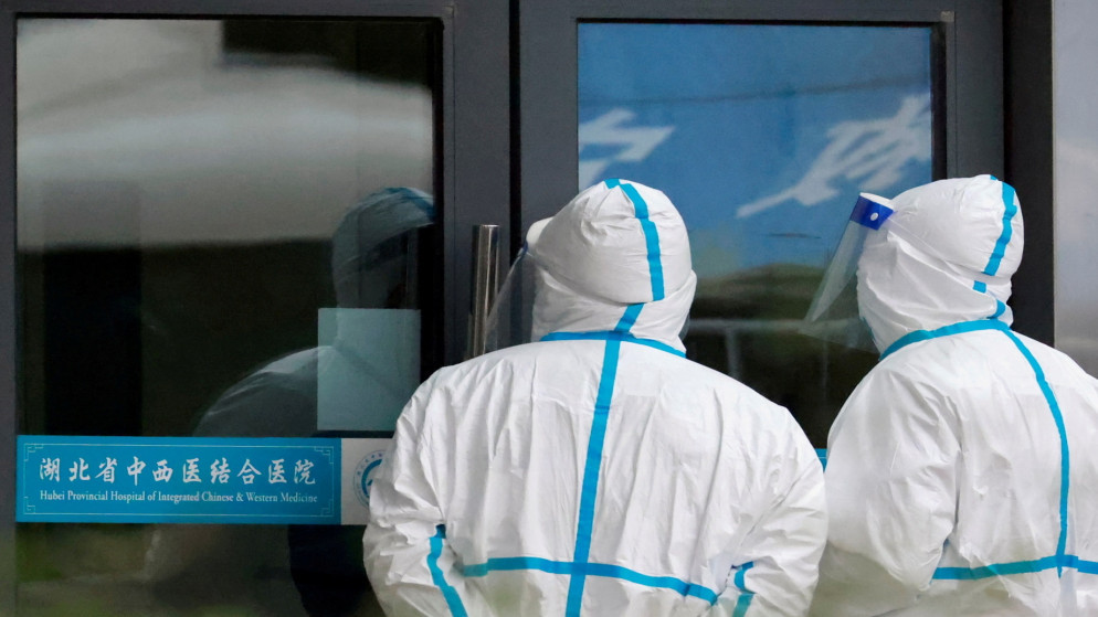 موظفون يرتدون بدلات واقية يقفون في مستشفى مقاطعة هوبى حيث يزور أعضاء فريق منظمة الصحة العالمية المكلف بالتحقيق في أصول مرض فيروس كورونا في ووهان، الصين، 29 يناير / كانون الثاني 2021. (رويترز / توماس بيتر)