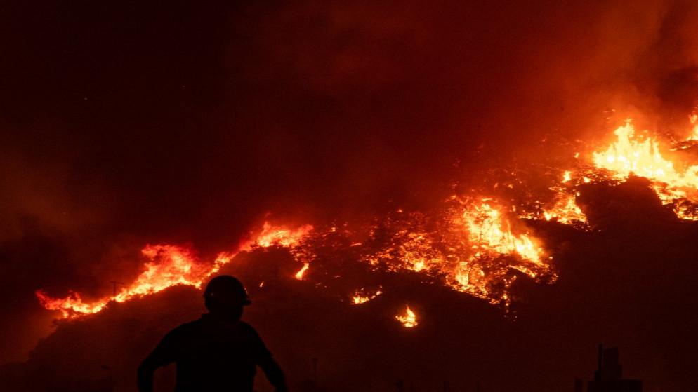 رجل إطفاء يسير على طول طريق ترابي خلال مكافحته حريقًا مشتعلًا بالقرب من محطة كيميركوي للطاقة الحرارية، في أورين بالقرب من بلدة ميلاس. تركيا.4 أغسطس 2021.(ا ف ب)