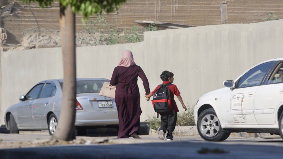 صورة أرشيفية لأم توصل طفلها إلى المدرسة في عمّان. (صلاح ملكاوي / المملكة)
