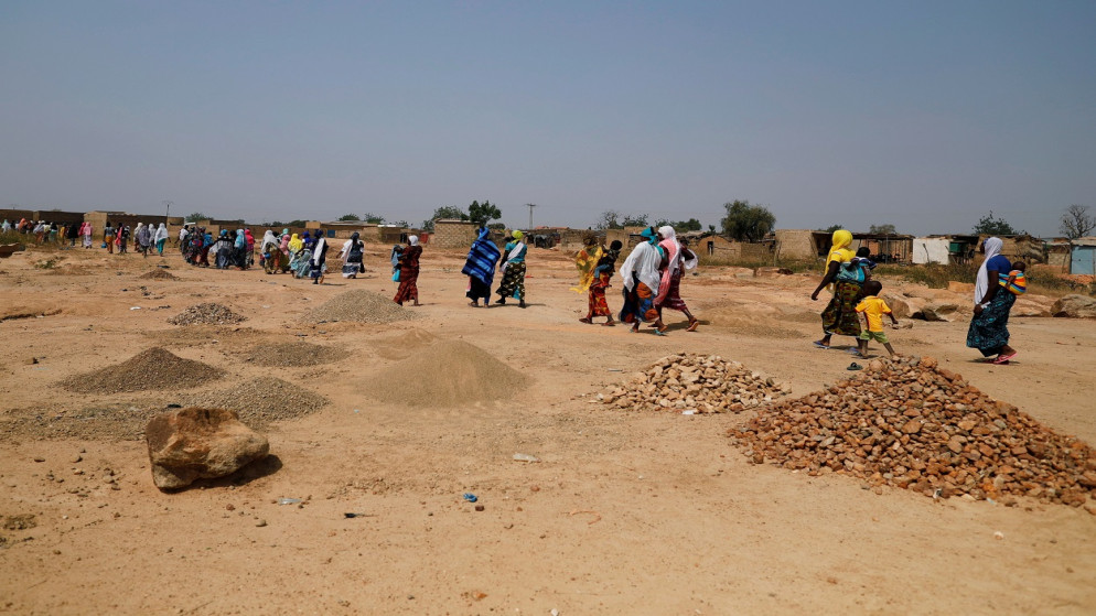 نساء فررن من هجمات شنها مسلحون في منطقة الساحل في سوم يسيرون في مخيم غير رسمي للنازحين في ضواحي واغادوغو، بوركينا فاسو، 19 تشرين الثاني/ نوفمبر 2020. (رويترز)