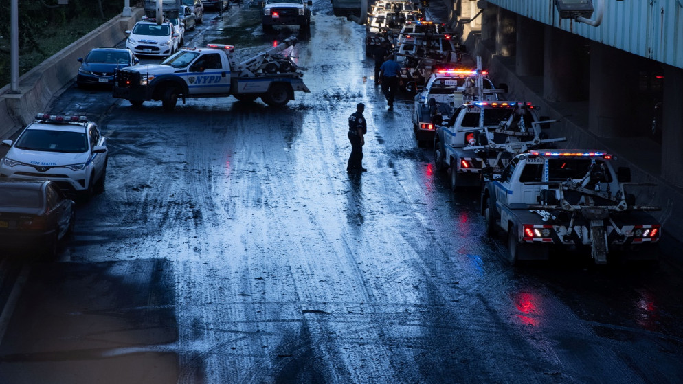 أحد أعضاء شرطة نيويورك يشرف على سحب شاحنات ومركبات عالقة على طريق ديجان السريع الرئيسي، في منطقة برونكس بمدينة نيويورك بالولايات المتحدة. 2 أيلول/سبتمبر 2021. (رويترز)