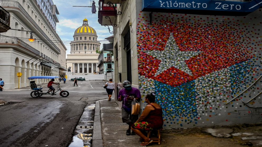 شخص بالقرب من كتابات على جدران ويظهر العلم الكوبي في أحد شوارع هافانا.12 يوليو / تموز 2021.(أ ف ب)