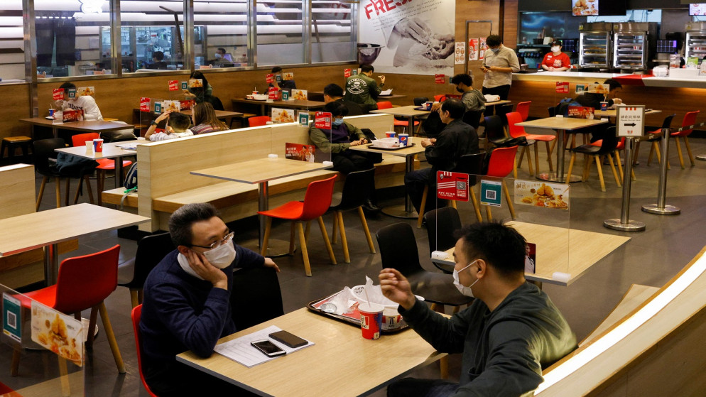 أشخاص يرتدون كمامات على طاولات عليها ألواح لتقسيم الطاولات داخل مطعم في هونغ كونغ، الصين، 5 كانون الثاني/ يناير 2022 (رويترز)