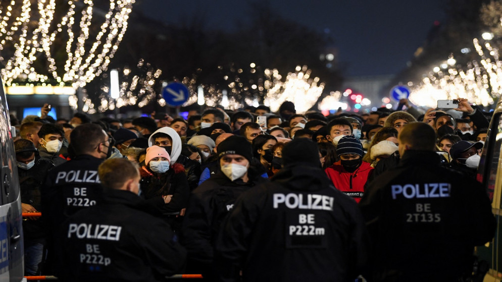 أشخاص يرتدون الكمامات بالقرب من بوابة براندنبورغ خلال احتفالات رأس السنة الجديدة، في برلين، ألمانيا، 31 كانون الأول/ ديسمبر 2021. (رويترز)