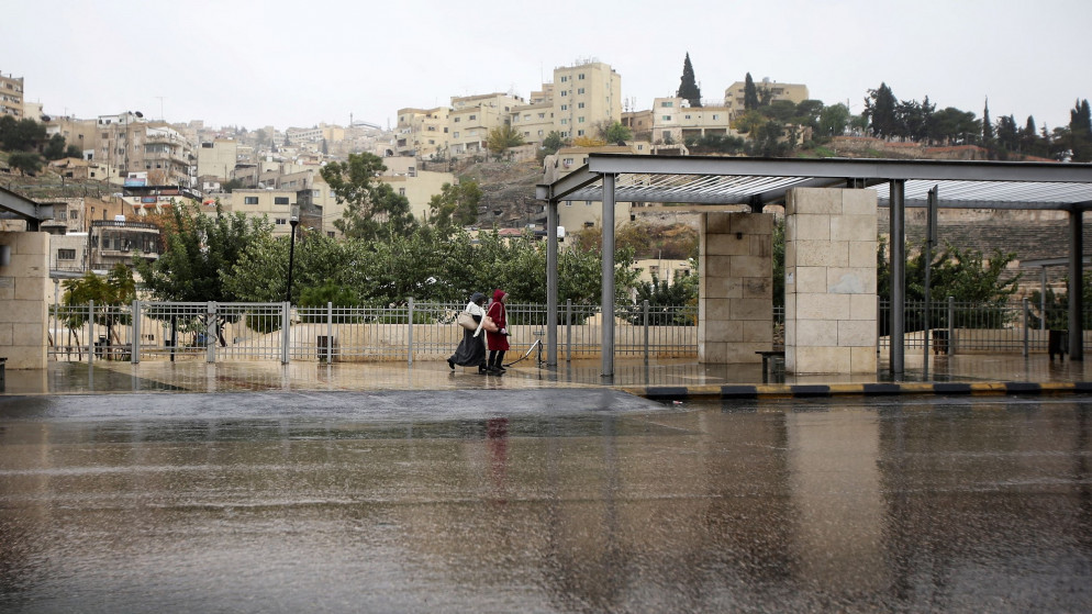 سيدتان تسيران في شارع وسط البلد خلال جو ماطر. (صلاح ملكاوي/المملكة)