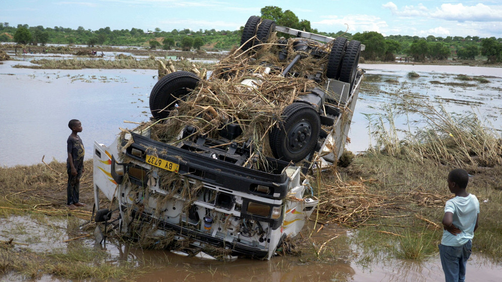 أشخاص ينظرون إلى حطام مركبة جرفتها المياه أثناء عاصفة استوائية آنا على نهر شاير الذي غمرته الفيضانات، في منطقة شيكواوا، جنوب مالاوي، 26 كانون الثاني/ يناير 2022. (رويترز)