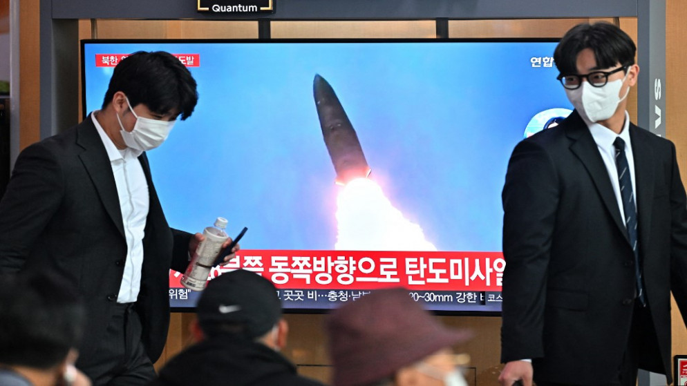 أشخاص يسيرون أمام شاشة تلفاز تُظهر لقطات لتجربة صاروخ كوري شمالي. 04/10/2022. (جونغ يون جي / أ ف ب)