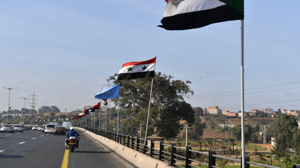 العلم السوري بين الأعلام المرفوعة في الجزائر تزامنا مع القمة العربية. (أ ف ب)