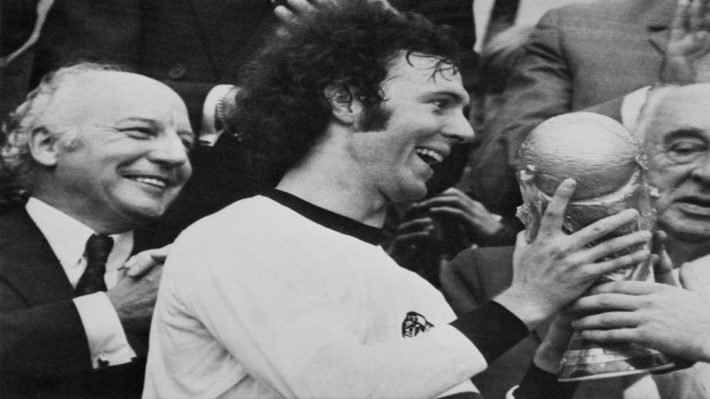 قائد المنتخب الألماني فرانتس بكنباور يحمل كأس العالم عام 1974 بعد فوز ألمانيا الغربية في النهائي على هولندا في ميونيخ. (أ ف ب)