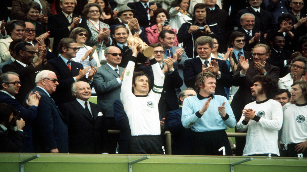 قائد المنتخب الألماني فرانتس بكنباور يحمل كأس العالم عام 1974 بعد فوز ألمانيا الغربية في النهائي على هولندا في ميونيخ. (فيفا)