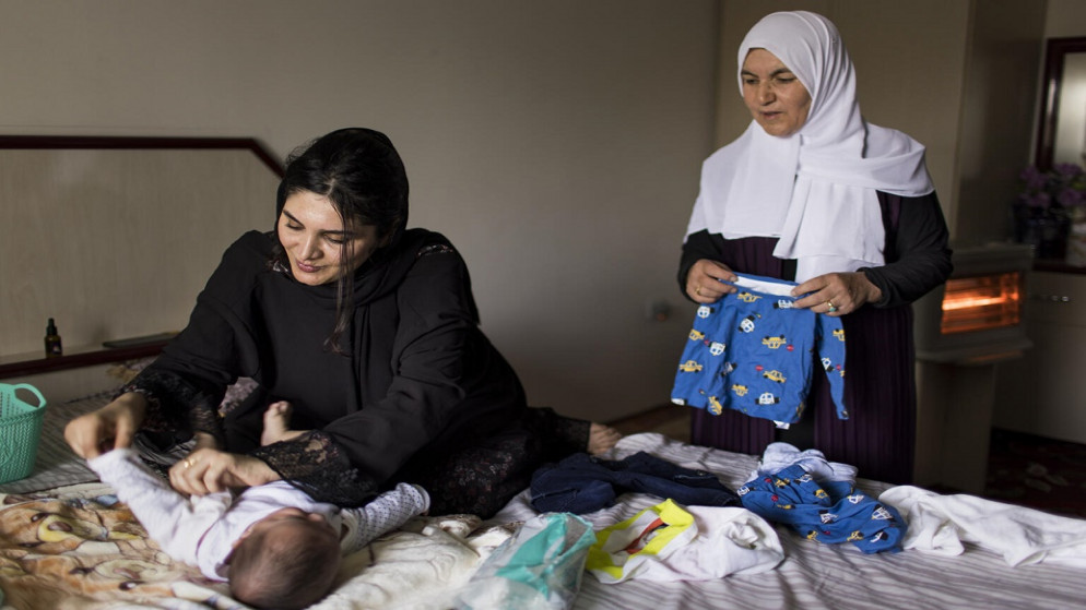 محمد وهو بعمر 6 أشهر في سرير بينما مع والدته سازان وجدته في السليمانية في العراق. (يونيسف)