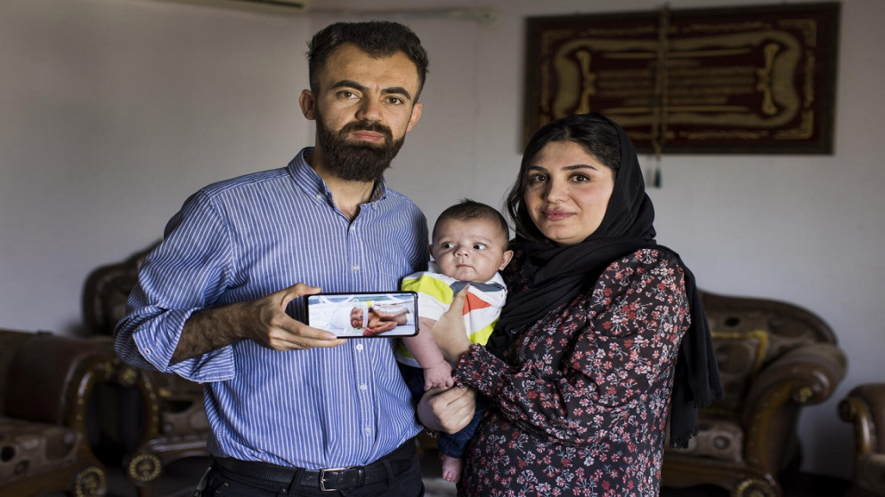 زهير وسازان يحملان محمد بعمر 6 أشهر وعلى الهاتف صورة محمد عندما كان في الحاضنة. (يونيسف)