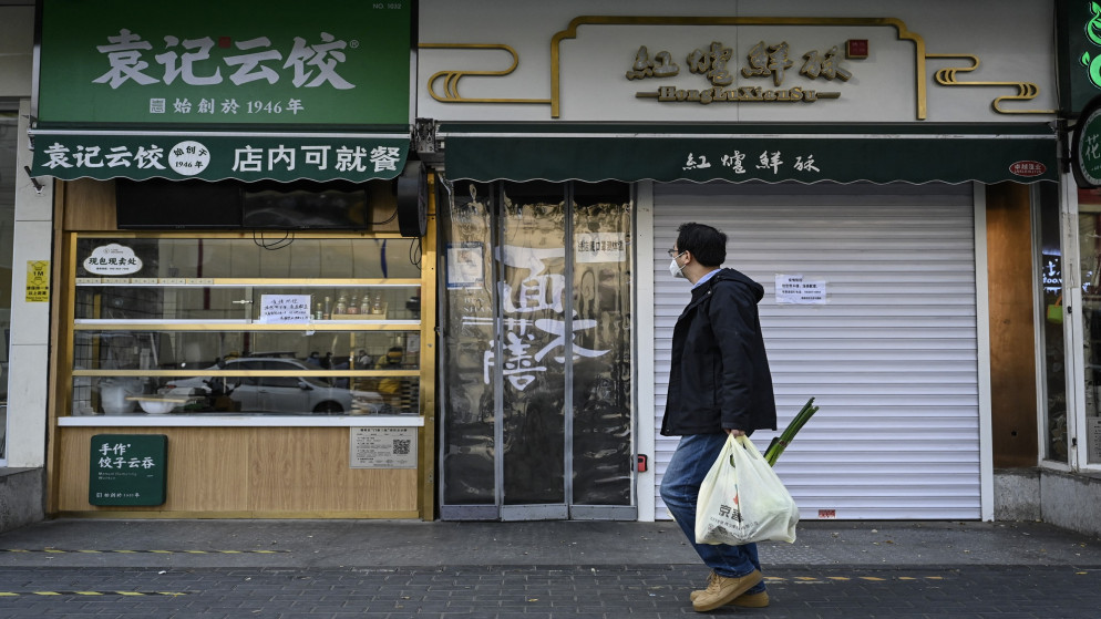 رجل يمشي أمام متاجر مغلقة في منطقة تشاويانغ ببكين بسبب قيود فيروس كورونا. 19 نوفمبر 2022. (أ ف ب)