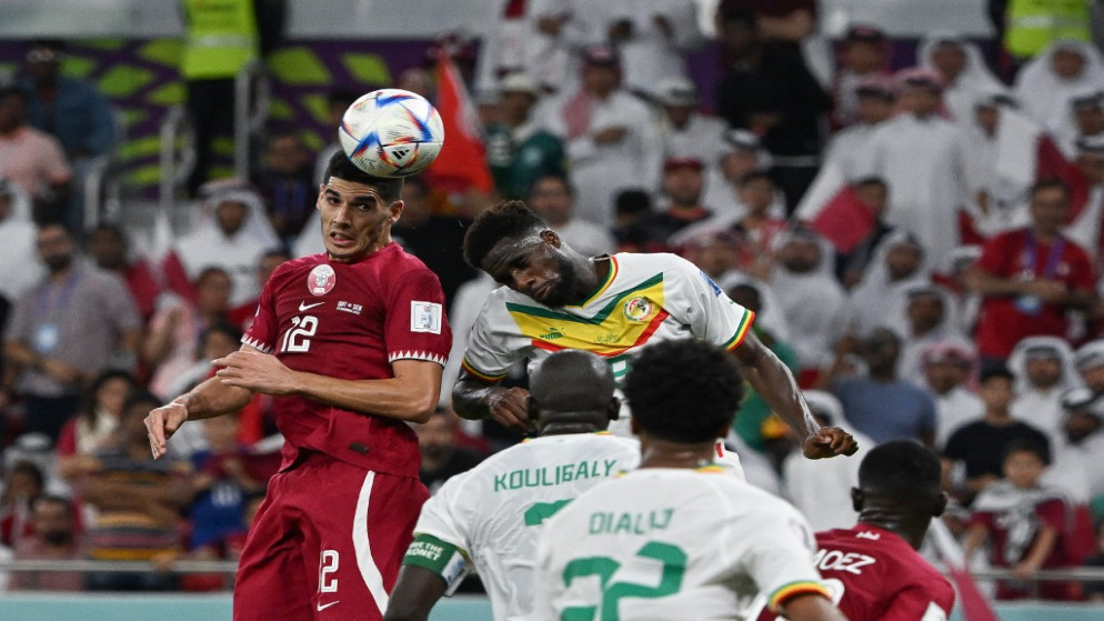 قفز لاعب الوسط القطري كريم بوضياف (يسار) والمهاجم السنغالي بولاي ضيا لرأس الكرة خلال مباراة قطر 2022 في المجموعة الأولى لكرة القدم بين قطر والسنغال على استاد الثمامة في الدوحة، 25 تشرين الثاني/نوفمبر 2022.