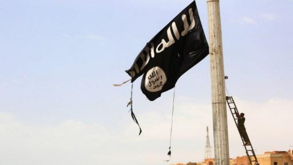 أحد أفراد قوات سوريا الديمقراطية ينزل علم تنظيم "داعش" الإرهابي بعد دحره من مناطق في مدينة الرقة، 30 تموز/يوليو 2017. (أ ف ب)