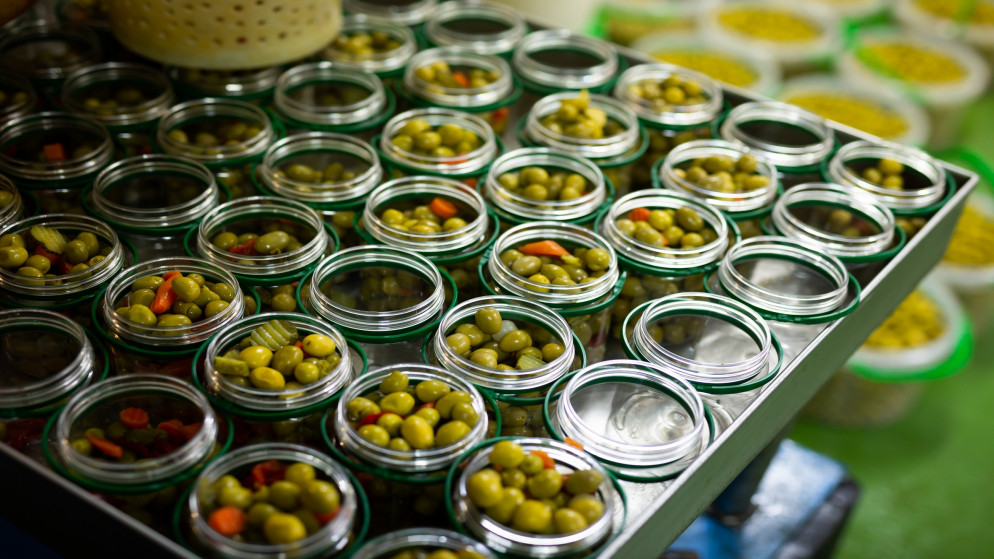 صورة توضيحية لعبوات زجاجية مليئة بالزيتون الأخضر في مصنع لإنتاج المخللات. (shutterstock)