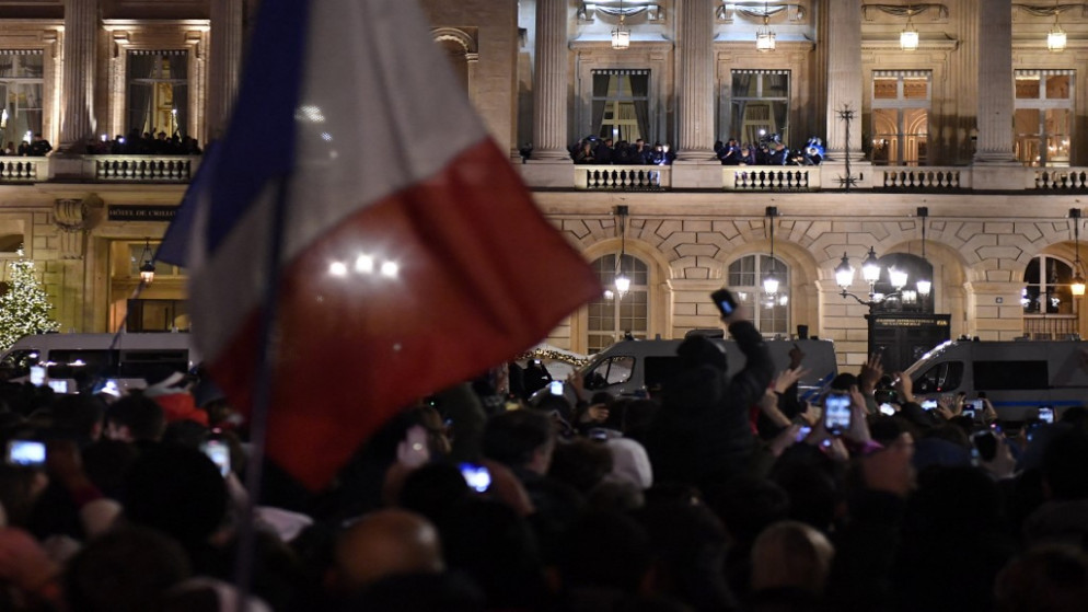 المشجعون، الذين يقفون في ساحة الكونكورد، يحيون المنتخب الفرنسي لكرة القدم في فندق دي كريون، بعد يوم واحد من المباراة النهائية لكأس العالم قطر 2022، ضد الأرجنتين، في وسط باريس، 19 ديسمبر 2022. (أ ف ب)