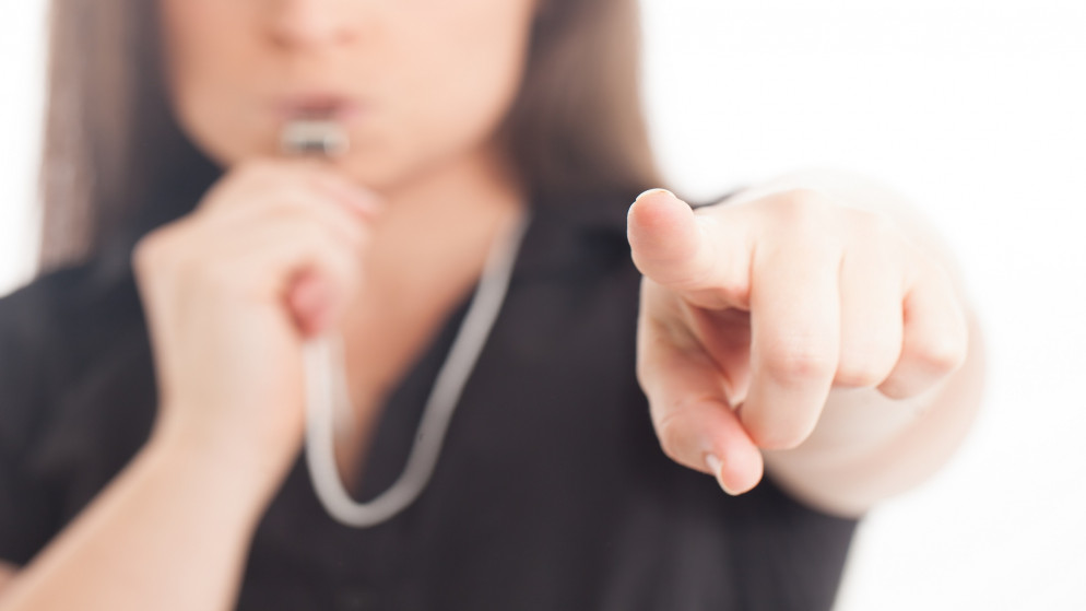 صورة توضيحية لفتاة وبيدها صفارة تحكيم. (shutterstock)