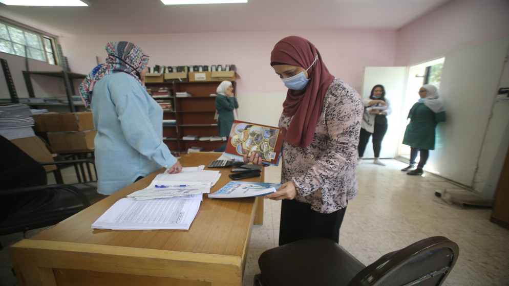 صورة أرشيفية لمعلمات يوزعن الكتب المدرسية على طلبات في أحد مدارس عمّان. (صلاح ملكاوي/ المملكة)