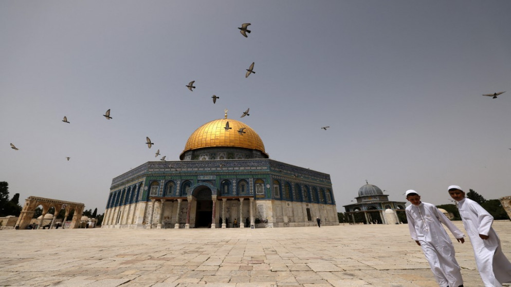 فلسطينيون يسيرون أمام مسجد قبة الصخرة في المسجد الأقصى في القدس .17 أبريل/نيسان 2022.(أ ف ب)